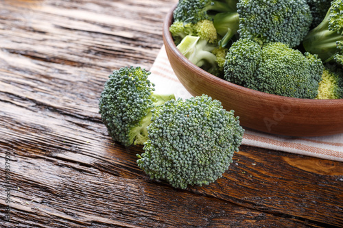 broccoli in a clay plate on a wooden table, next to a whole cabbage are cut inflorescences . top view