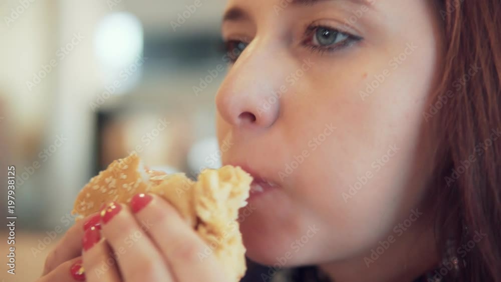 woman eating a hamburger in a cafe woman eating a hamburger in a cafe