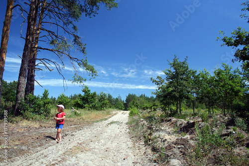A little girl is walking on the country road barefoot