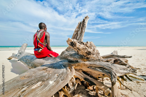 man of the Maasai tribe sits on the shore of the Indian ocean photo