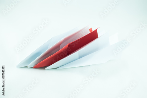 Red paper plane among white ones on a white background, isolated. Concept (idea) of airlines, freedom, leadership, success, and individualism.