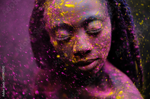 African woman with colourful powder on her face and body.