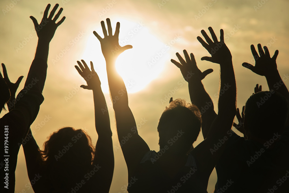 Dancing people at rock concert. Young people with hands up looking at the sun while sunset.