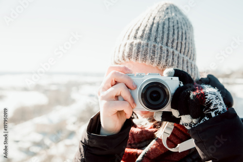 Woman tourist photographer is taking a photo by white mirrorless digital camera © Ivan Kurmyshov