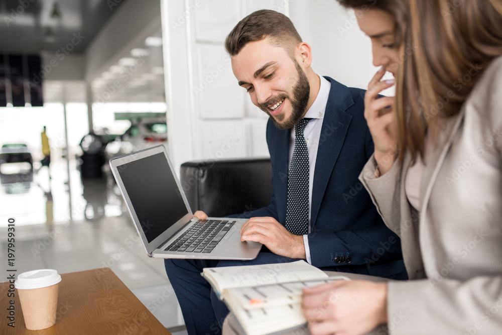 Portrait of two modern business people, man and woman, using laptop and working sitting at coffee table in office Portrait of two modern business people, man and woman, using laptop and working sitting at coffee table in office
