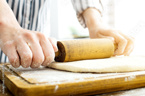 Female hands making dough on kitchen background