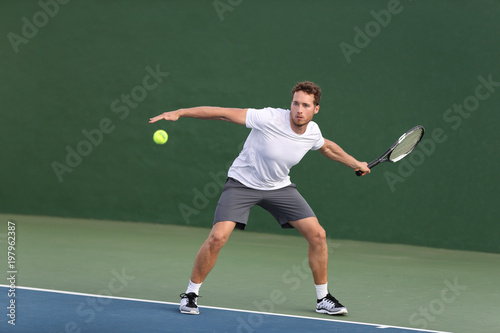 Professional tennis player athlete man hitting forehand ball on hard court playing tennis match. Sport game fitness lifestyle person living an active summer lifestyle. © Maridav