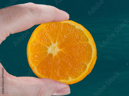 Orangenscheibe in der Hand grüner Hintergrund