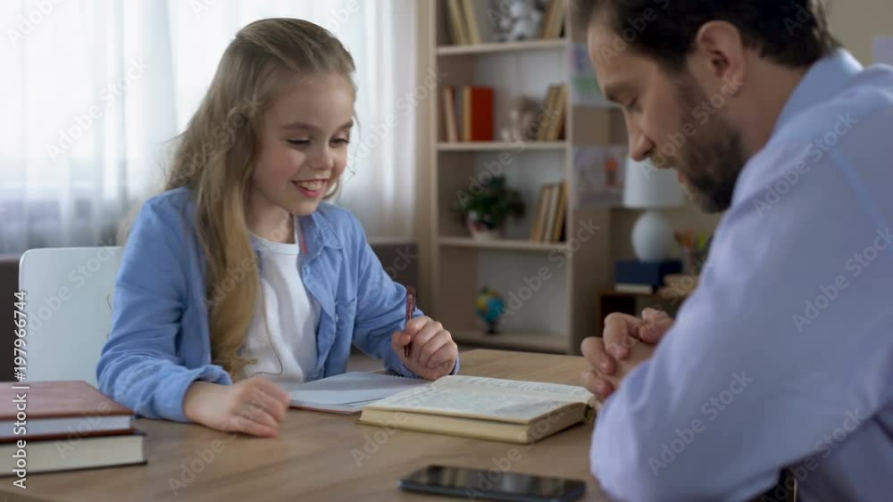 Caring dad helping his smiling daughter to do homework, paternal support Caring dad helping his smiling daughter to do homework, paternal support