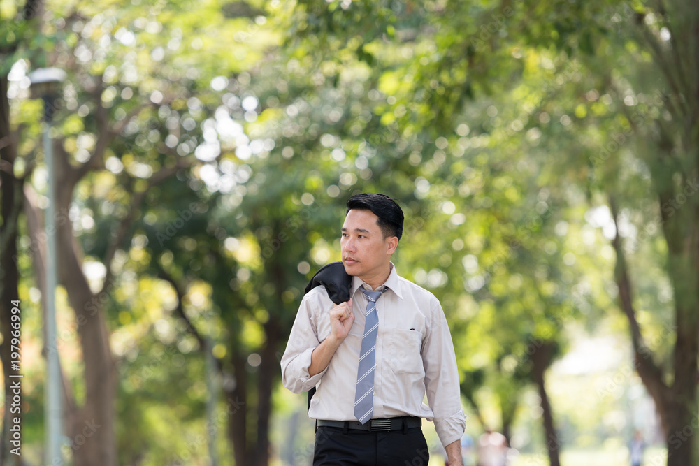 Young Asia businessman showing stress face. He was walking in the Park.. Young Asia businessman showing stress face. He was walking in the Park..