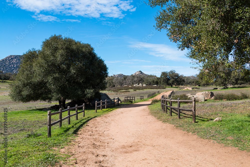 A dirt road lined by wooden fencing at Ramona Grasslands Preserve in San Diego, California. A dirt road lined by wooden fencing at Ramona Grasslands Preserve in San Diego, California.