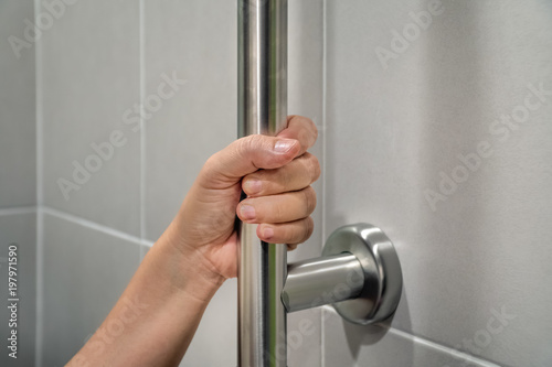 Woman holding on handrail in toilet.