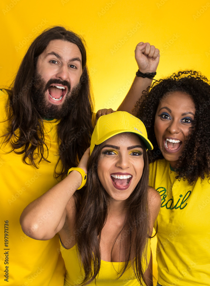 Φωτογραφία Brazilian group of fans celebrating on football match on yellow background