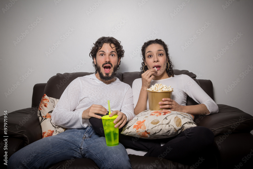 Heterosexual couple is eating popcorn and watching movie at home. Scared.. Heterosexual couple is eating popcorn and watching movie at home. Scared..