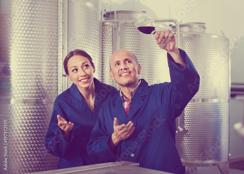Mature man and women coworkers looking at wine in glass