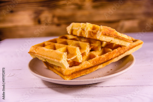 Ceramic plate with belgian waffles on wooden table