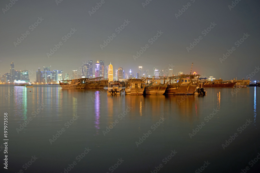 Traditional Dhows in front of nightly Doha Skyline