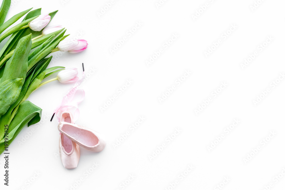 Ballet shoes near delicate flowers on white background top view copy space