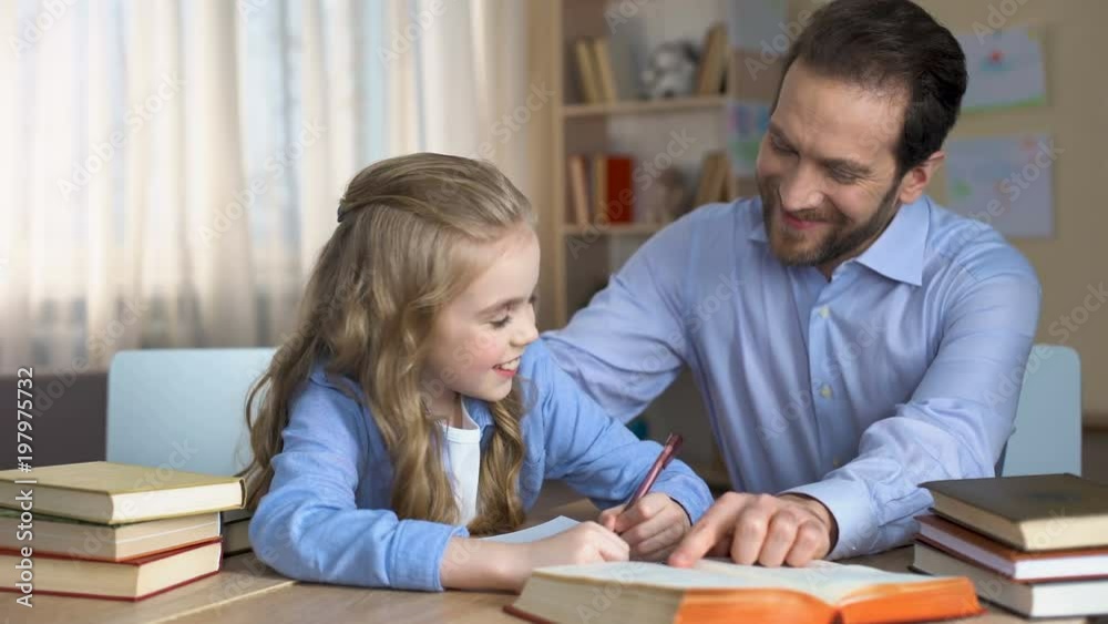 Happy female child doing homework with her caring daddy, support and love Happy female child doing homework with her caring daddy, support and love