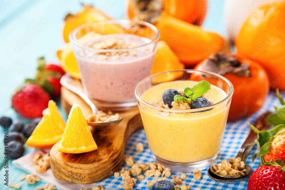 Orange persimmon blueberry smoothie with granola and fruits. Selective focus. Copy space Orange persimmon blueberry smoothie with granola and fruits. Selective focus. Copy space