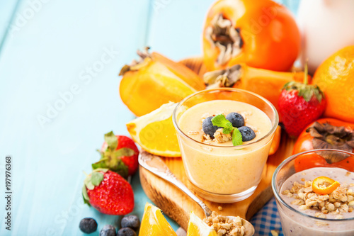Orange persimmon blueberry smoothie with granola and fruits. Selective focus. Copy space