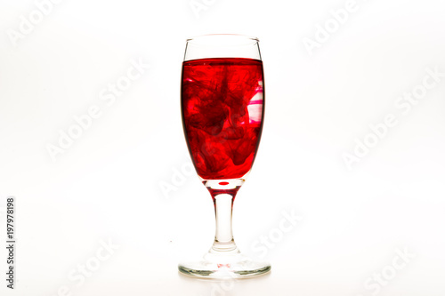 Red food coloring diffuse in water inside wine glass with empty copy-space area for slogan or advertising text message  over isolated white background.
