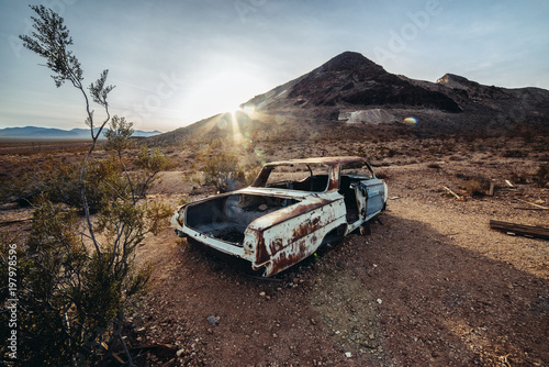 Old rusty abandoned car in the desert at sunset time
