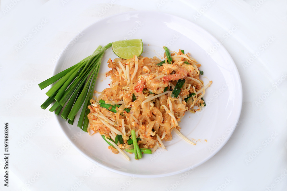 Pad Thai, stir-fried rice noodles with shrimp in white plate with slide lemon and green vegetable. The one of Thailand's national main dish. the popular food in Thailand. Thai Fried Noodles