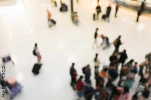blurred image of crowd of travelling people or passenger walking with a luggage from flight in the international airport terminal with beautiful bokeh from the light,advertise & traveling concept.