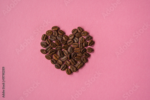 Coffee beans shaped hearts on a pink background. Love coffee concept