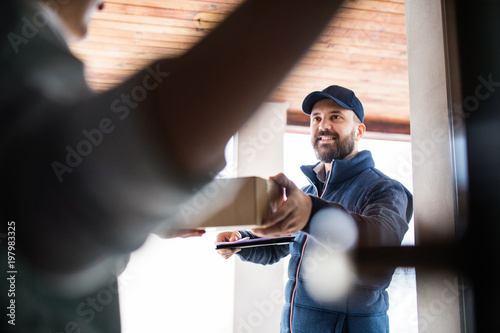 Woman receiving parcel from delivery man at the door.