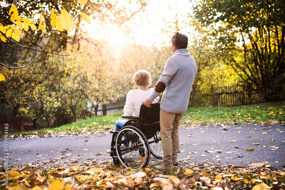 Senior couple in wheelchair in autumn nature.