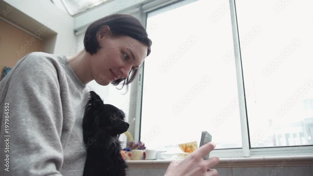 Young girl taking selfie with cute black pet chihuahua lap dog in living room Young girl taking selfie with cute black pet chihuahua lap dog in living room
