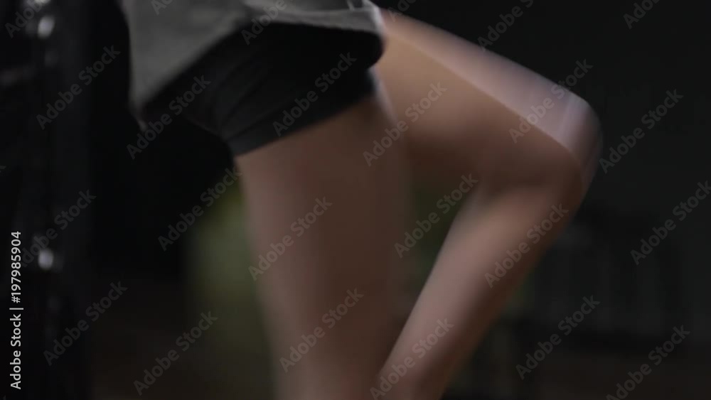 Medium shot of young woman in sports clothes warming up before boxing workout at the gym and doing high knee jumps Medium shot of young woman in sports clothes warming up before boxing workout at the gym and doing high knee jumps