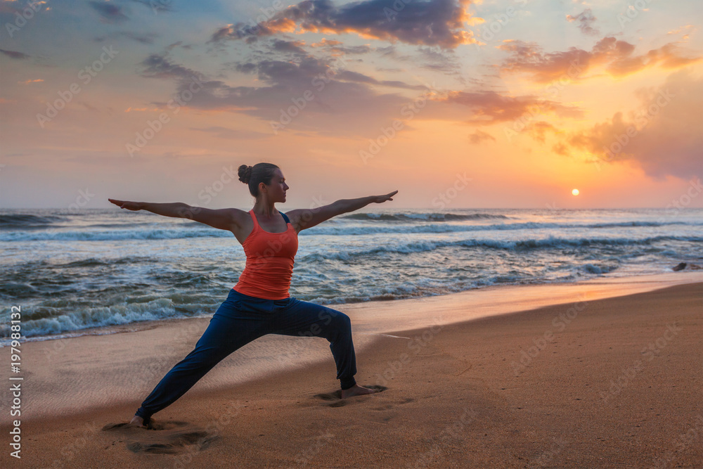 Woman doing yoga asana Virabhadrasana 1 Warrior Pose on beach on