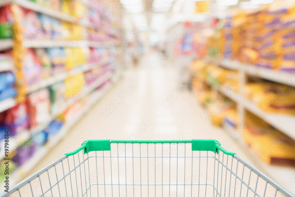 Shopping cart with abstract blur supermarket discount store aisle and pet food product shelves interior defocused background