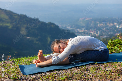 Woman doing yoga asana Paschimottanasana forward bend