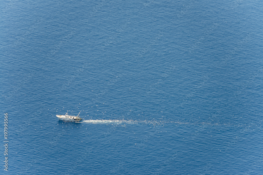 Aerial image of white fishing boat on the Tyrrhenian Sea between Italy and Corsica followed by gulls Aerial image of white fishing boat on the Tyrrhenian Sea between Italy and Corsica followed by gulls
