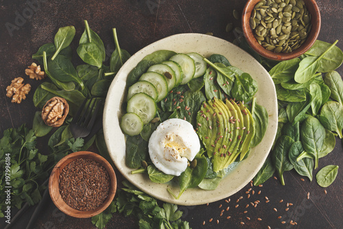 Green salad with spinach, cucumber, avocado, egg, flax and pumpkin seed. Food background. Detox Vegetarian Healthy Food Concept. Top view, copy space.