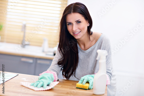 Beautiful young woman cleaning the kitchen