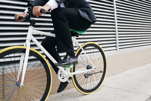 Unrecognizable businessman in suit commuting by bike