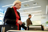 Side view portrait of pretty blonde businesswoman swiping card passing turnstile to enter building