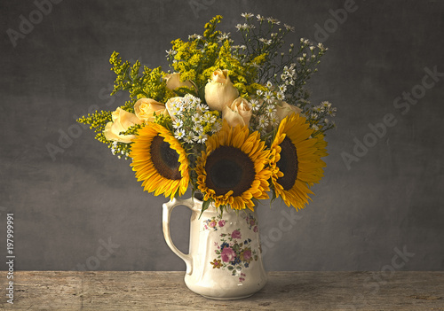 Sunflowers in an antique jug on a rustic wooden table