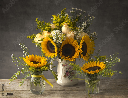 Sunflowers in an antique jug with jam jars