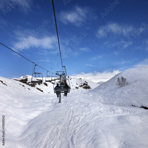 Chair-lift and off-piste slope in sun day
