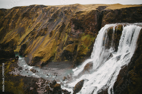 scenic icelandic landscape with majestic Fagrifoss waterfall and rocks with green vegetation