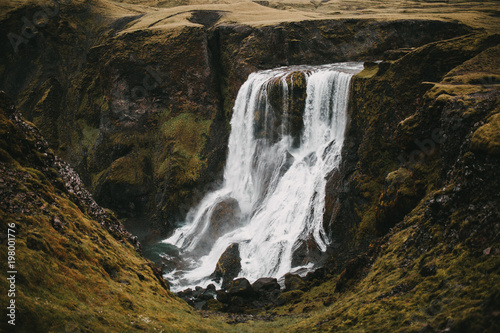 beautiful icelandic landscape with scenic Fagrifoss waterfall and rocks with green vegetation