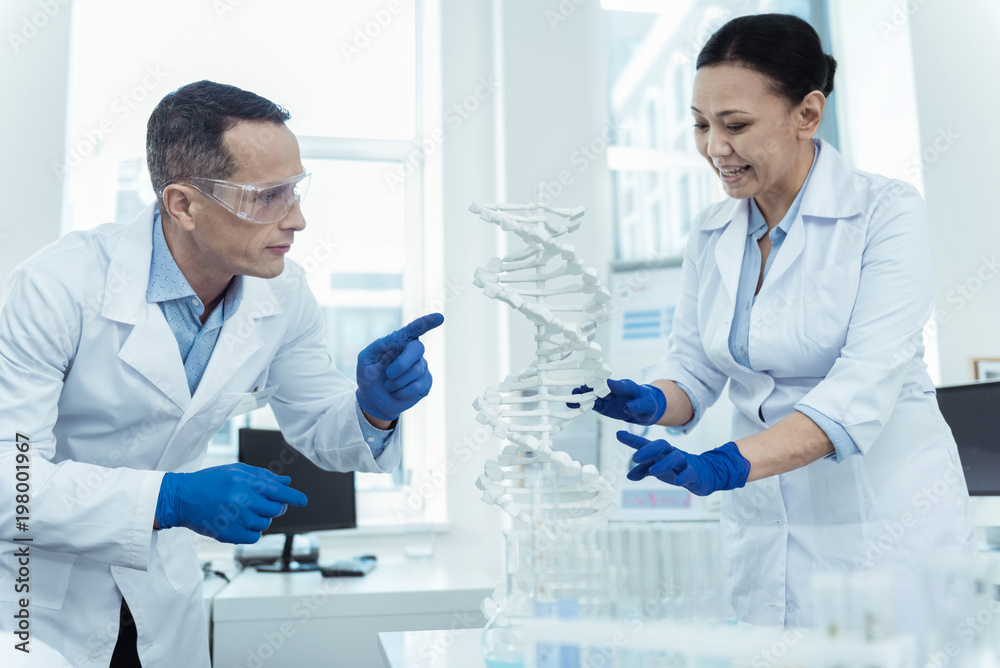 Study precisely. DNA diagnostic. Professional scientists studying dna model in a lab environment Study precisely. DNA diagnostic. Professional scientists studying dna model in a lab environment