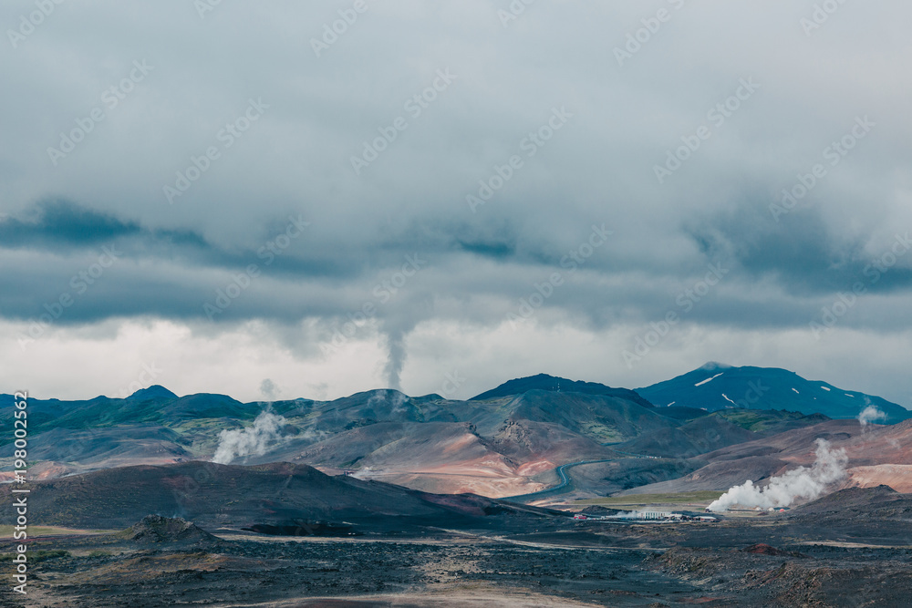 majestic icelandic landscape with mountains and steam from hot springs at cloudy day