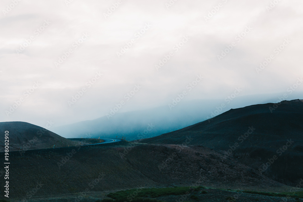 majestic icelandic landscape with hills and asphalt road at cloudy day